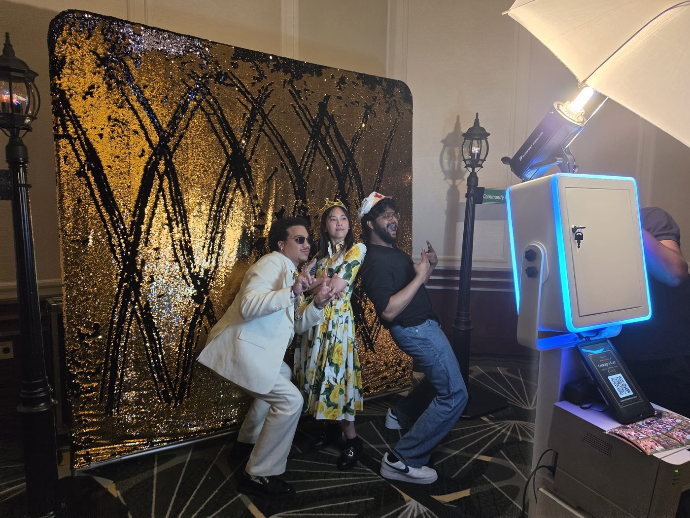 Guests having fun at the photobooth with a gold sequin backdrop